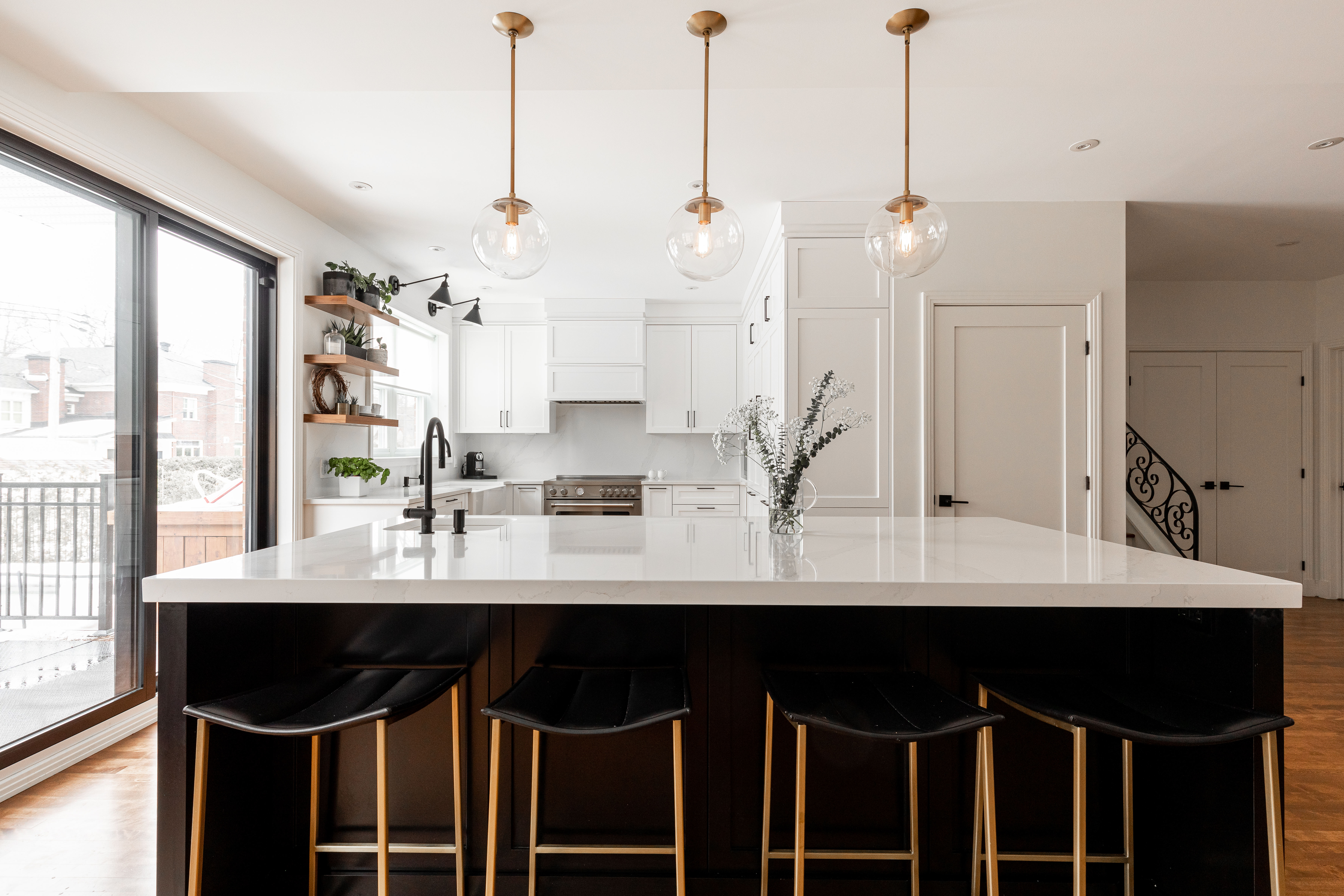 Modern kitchen. Golden-colored light fixtures are suspended above the central kitchen island.