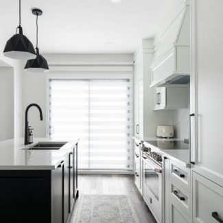 Modern open concept kitchen. The wardrobes of the island are black while those of the main structure are white.