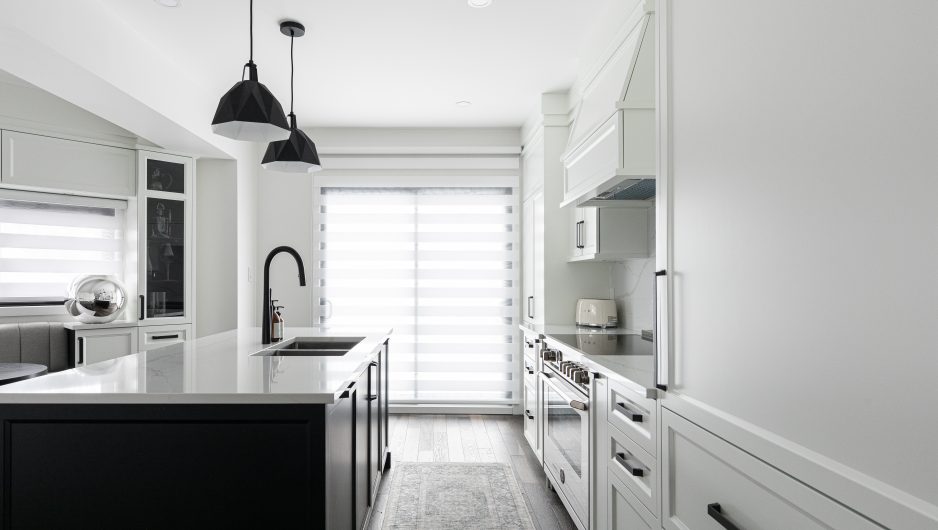 Modern open concept kitchen. The wardrobes of the island are black while those of the main structure are white.