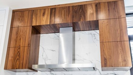 Contemporary kitchen design with a central island and stone backsplash.