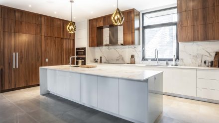 Contemporary white kitchen with central island and integrated sinks.