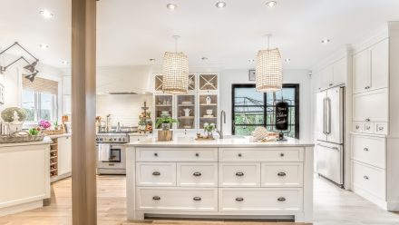 Cuisine de style champêtre réalisée par Ateliers Jacob. Les armoires de cuisine sont en MDF blanc que les insertions de bois sur certains éléments viennent réchauffer. Le comptoir de quartz complète le look avec une touche de finesse. Quelques plantes sont installés sur l'îlot central et les comptoirs.