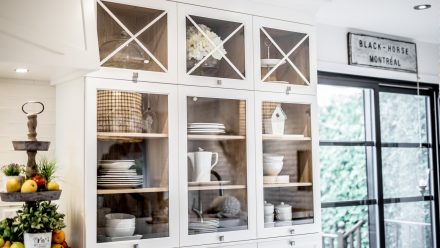 Armoires de cuisine en MDF blanc dont certaines portes sont en verre. La rangée la plus haute de l'armoire possède des portes vitrées dont le cadre se croise sur la vitre.