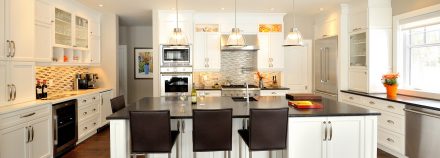 White kitchen with built-in cabinets and dark countertops in a bright room.