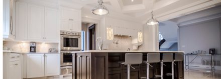 Completely furnished kitchen with central island and white cabinets.