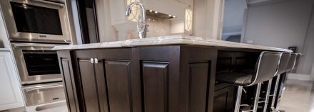 Kitchen with central island, dark cabinets and stone countertop.