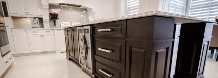 White furnished kitchen with central island and stone worktop.