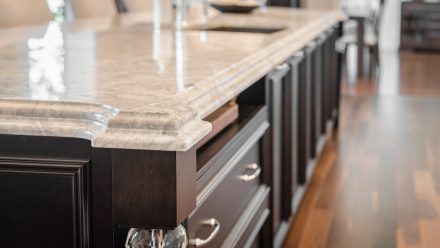 Spacious kitchen with dark cabinets, light countertops, and integrated lighting.