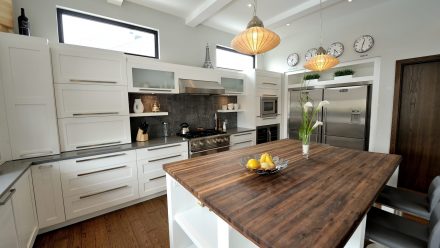 White kitchen with central island and integrated storage in a spacious room.