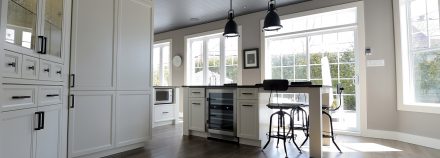 Sleek white kitchen with central island and suspended lighting.