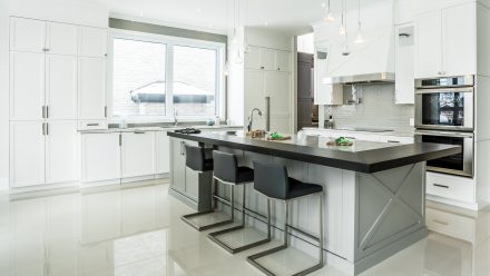 Spacious streamlined kitchen with central island and light-colored countertop.