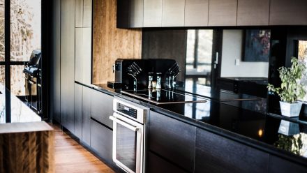 Contemporary Kitchen with dark countertops and streamlined cabinets.