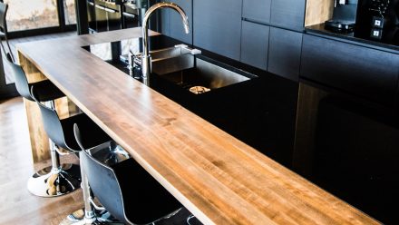 Dark kitchen with central island and undermount sink.