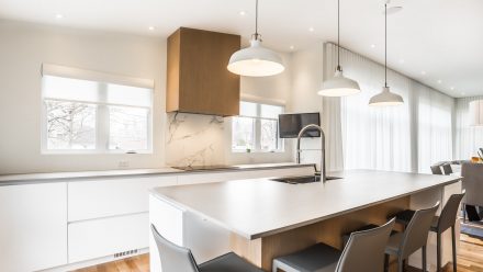 Cuisine design aux tons clairs avec îlot central et électroménagers haut de gamme.