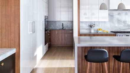 White kitchen with central island and built-in cabinets in a bright room.