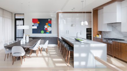 Cuisine moderne réalisée par Ateliers Jacob. Les armoires et la table en bois contrastent très joliment avec la blancheur du comptoir et du mur en marbre intégré.