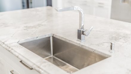 White kitchen with stone countertops and undermount sink.