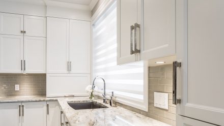 White kitchen with island, built-in storage and stone countertop.