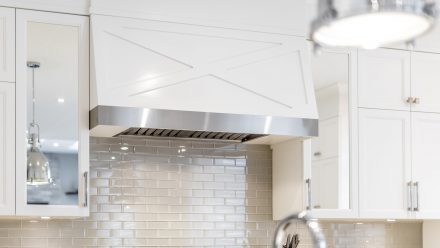 White kitchen with LED lighting under the cabinets and built-in hood.
