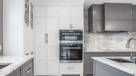 Kitchen with central island, white cabinets and natural stone countertop.