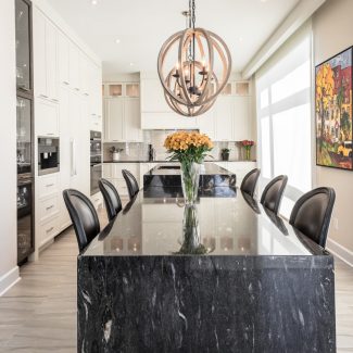 Spacious and bright kitchen with white cabinets, central island, and dining area.