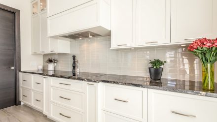 Refined kitchen with white and black cabinets and a dark stone countertop.