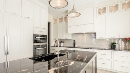 Kitchen fitted with white cabinets, a central island, and a dark stone countertop.