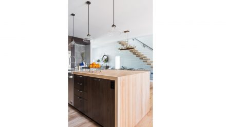 Modern Kitchen with a dark central island and light tinted wood.