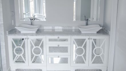 Une salle de bain avec des armoires blanches et un comptoir de pierre.