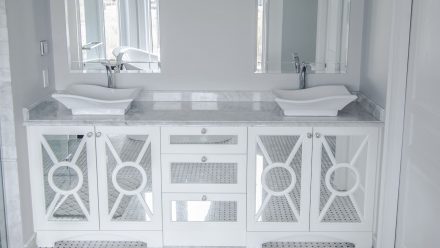 A bathroom with white cabinets and a stone countertop.