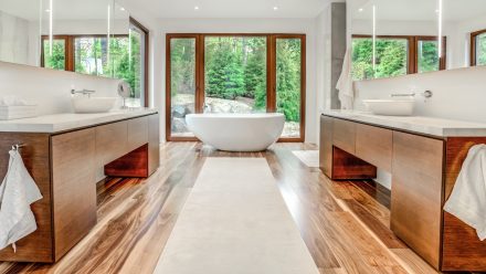 Salle de bain moderne avec armoires foncées et grands miroirs.