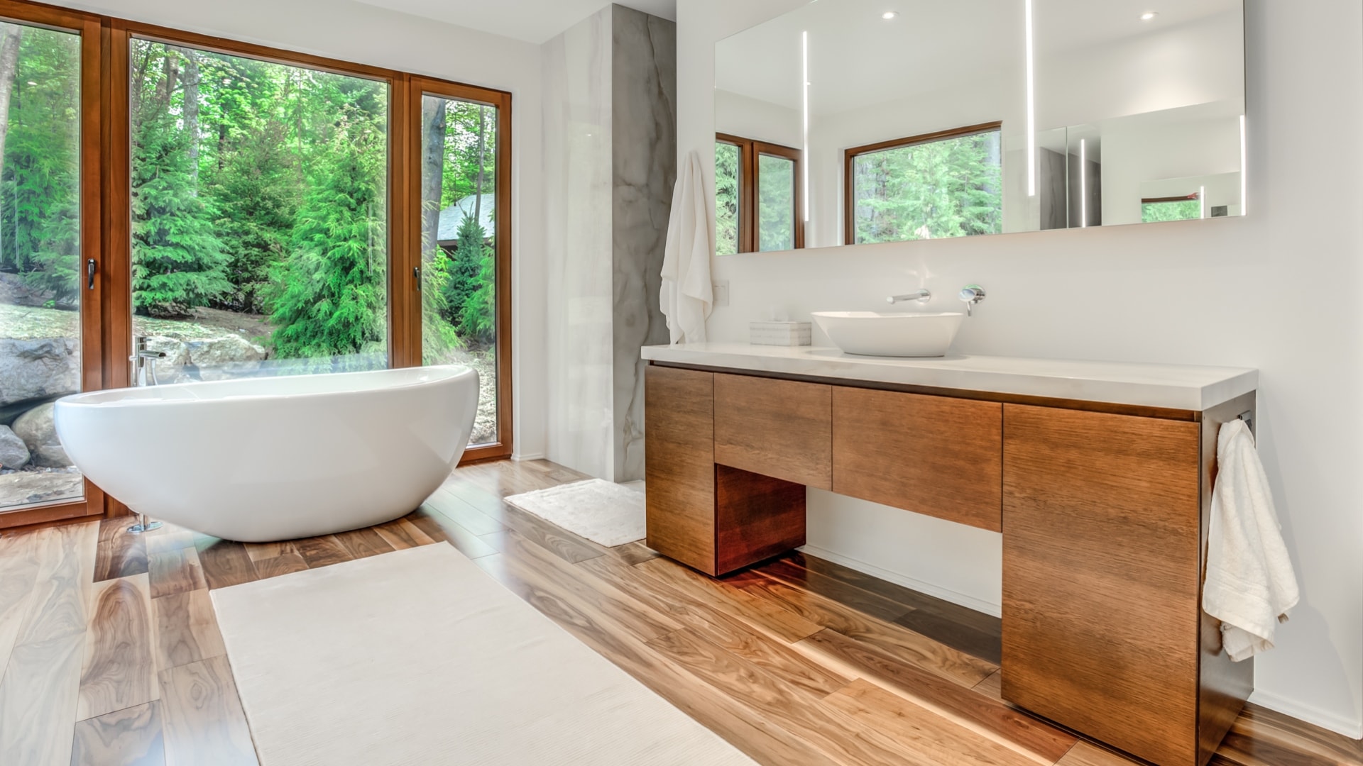 Salle de bain contemporaine en placage de chêne. Une grande baignoire autoportante tient place devant de grandes baies vitrées.