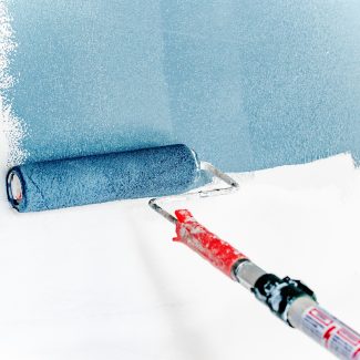 Rouleau de peinture bleue en action sur un mur blanc