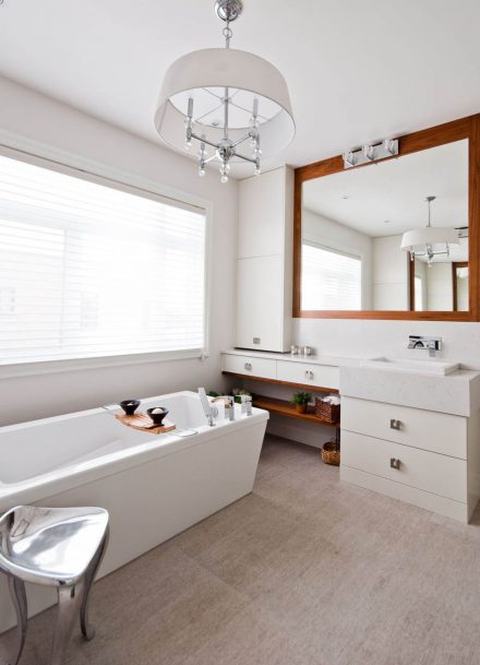 Salle de bain moderne avec armoires blanches et bain séparé.