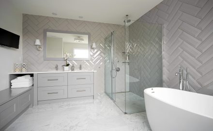 Salle de bain contemporaine avec armoires grises et douche séparée.