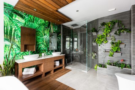 Salle de bain verdoyante aux armoires foncées et lavabos doubles.