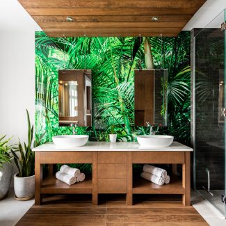 Green bathroom with dark cabinets and double sinks.