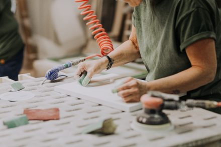 Une vieille femme travaillant sur une armoire en bois en usine