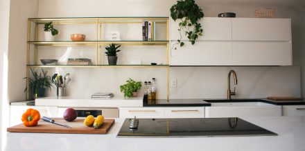 Modern white kitchen with black worktop and integrated appliances.