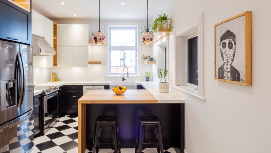 Cuisine urbaine réalisée par Ateliers Jacob. Les armoires de cuisine sont noires et blanches pour s'accorder au sol en damier. Le comptoir de l'îlot central est un épais bloc de boucher en merisier huilé qui contraste avec les autres comptoirs de la cuisine en dekton blanc.