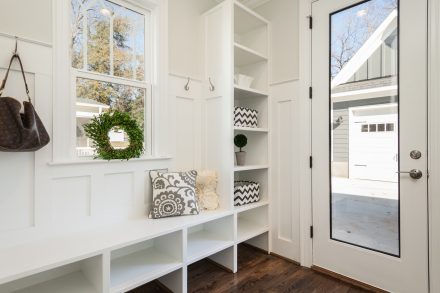 Mudroom dans le hall d'une maison comportant des armoires, des portants et un banc.