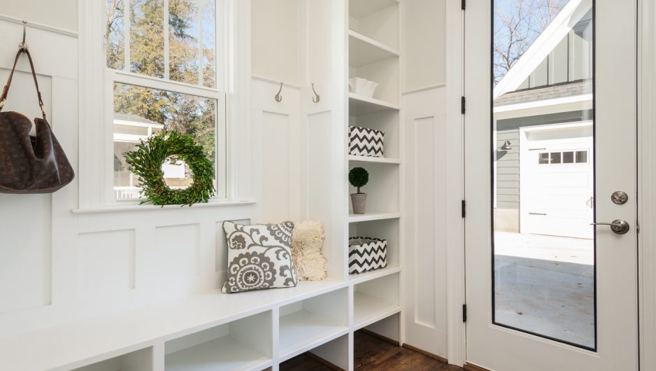 Mudroom dans le hall d'une maison comportant des armoires, des portants et un banc.