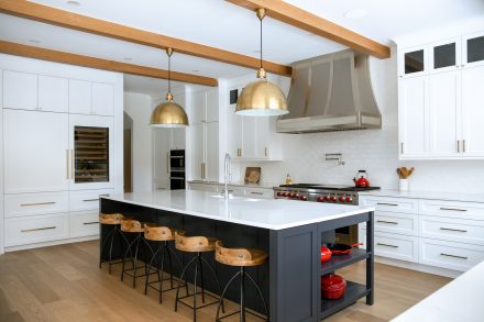 Modern white kitchen furniture with a dark central island and dining area.