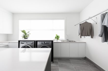 Modern sleek laundry room with central island and ample storage.