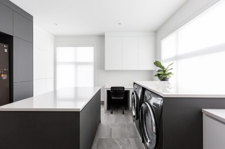 Modern sleek laundry room with central island and ample storage.