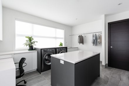 Modern sleek laundry room with functional storage and central island.