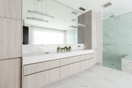 Modern bathroom furniture with light-colored cabinets and glass shower.