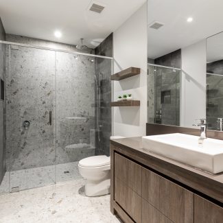 Layout of a modern and sleek bathroom with dark cabinets and a glass shower.
