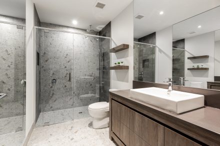 Layout of a modern and sleek bathroom with dark cabinets and a glass shower.