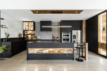 Interior of a furnished kitchen with dark countertops and elegant lighting.